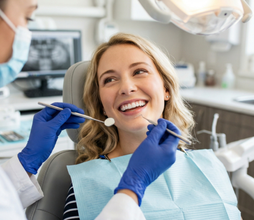 Smiling woman in a dental chair during a checkup with dental tools near her mouth in use by a dentist